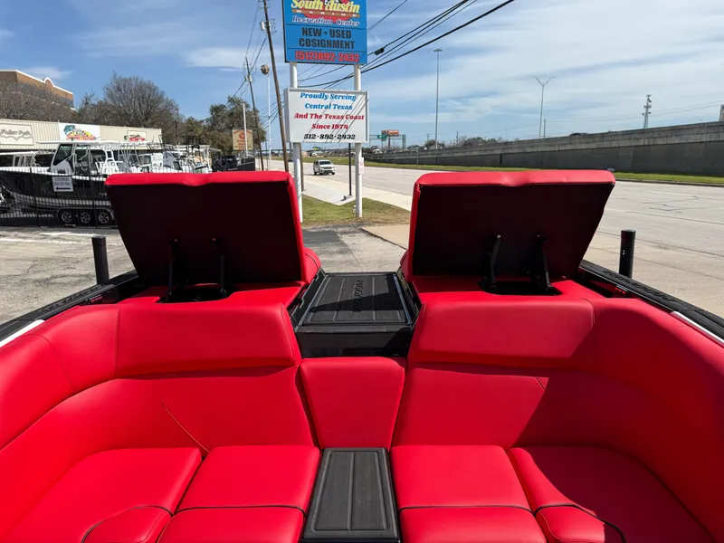 Slide: The Image of 2025 Moomba Tykon boat with vibrant red seating, open compartments, and a street view background. - 29