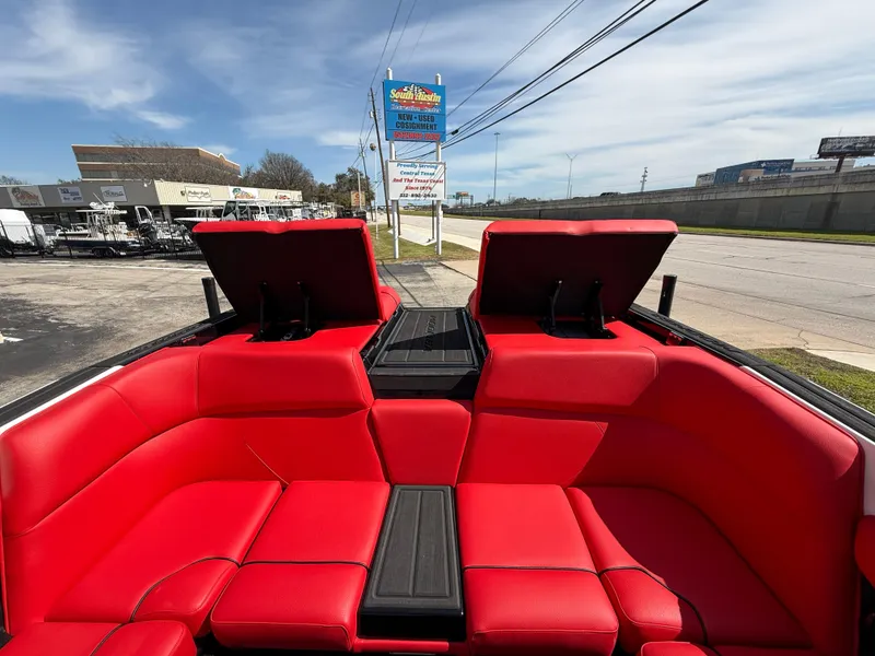 Slide: The Image of 2025 Moomba Tykon boat interior with vibrant red seating and open storage compartments. - 30