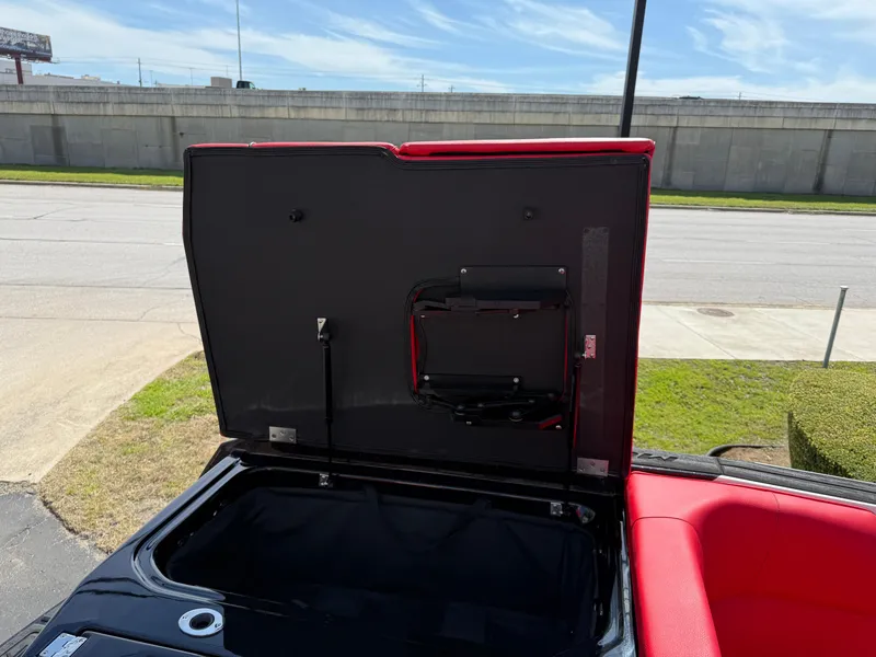 Slide: The Image of 2025 Moomba Tykon boat storage compartment with open lid, featuring red interior accents. - 31