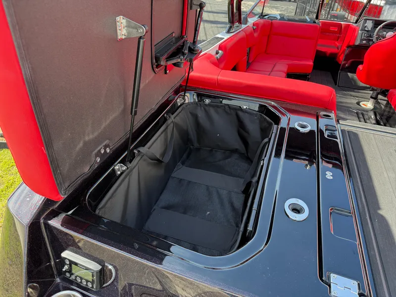 Slide: The Image of 2025 Moomba Tykon interior with open storage compartment and red seating. - 35