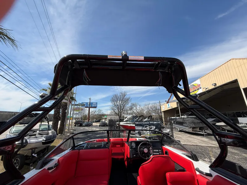 Slide: The Image of 2025 Moomba Tykon boat with red interior, parked outdoors under a clear blue sky. - 37