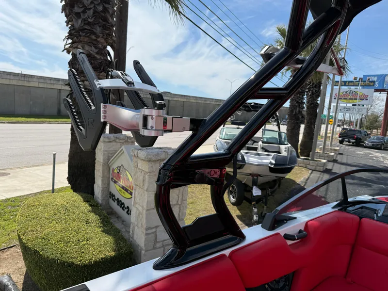 Slide: The Image of 2025 Moomba Tykon boat with red interior and wakeboard rack, parked outdoors. - 39