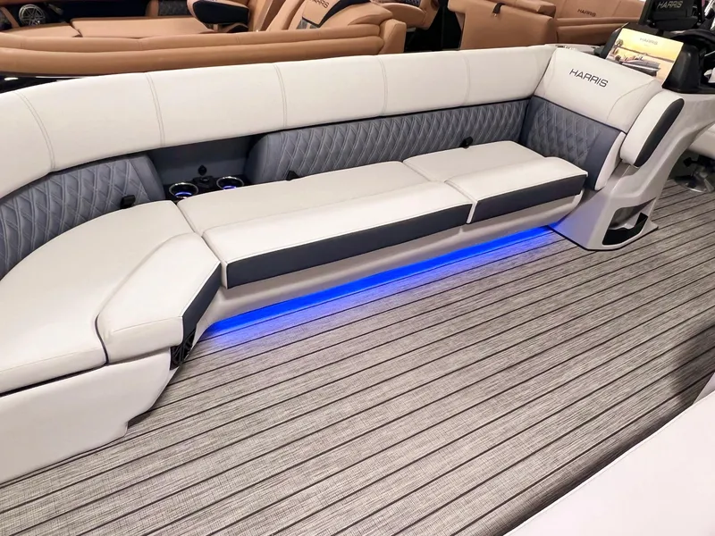 Slide: The Image of 2024 Harris Sunliner 250 boat interior with plush seating and ambient blue lighting. - 28