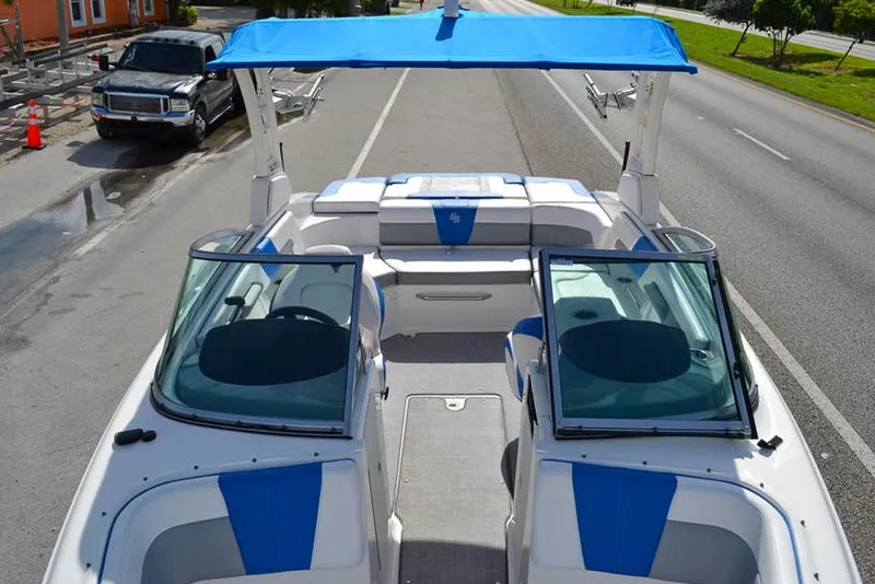 Slide: The Image of 2021 Chaparral 23 Surf boat with blue accents and canopy on a road. - 22