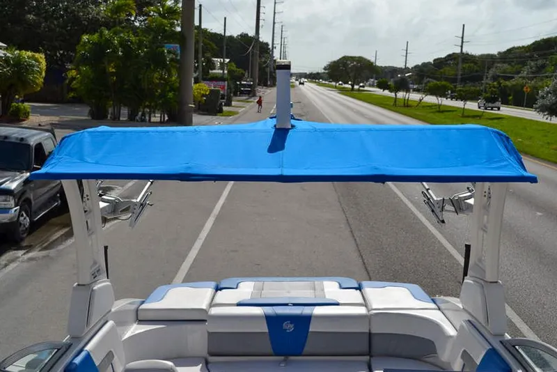 Slide: The Image of 2021 Chaparral 23 Surf boat with blue canopy on a road. - 23