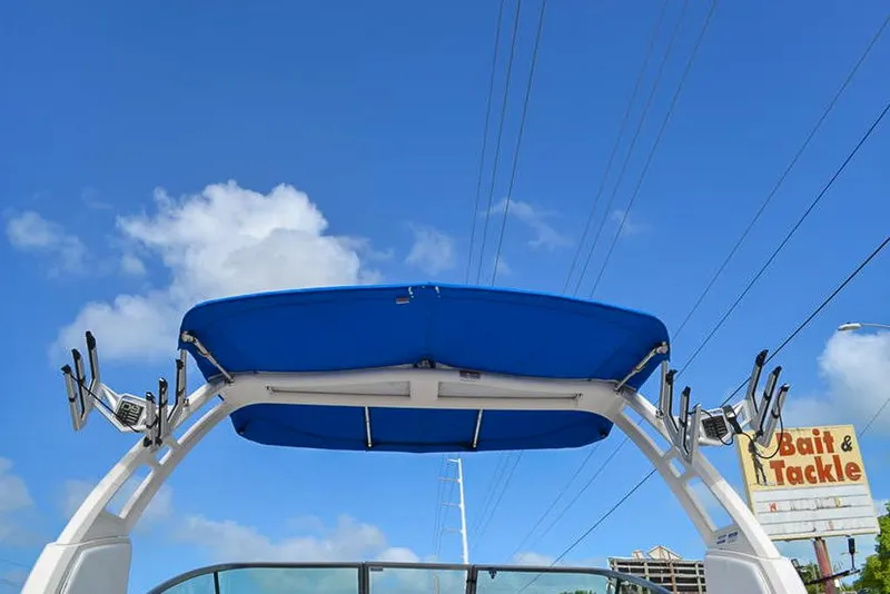 Slide: The Image of 2021 Chaparral 23 Surf boat with blue canopy against a clear sky. - 26