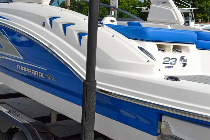 Slide: The Image of 2021 Chaparral 23 Surf boat with blue and white design on a trailer. - 32