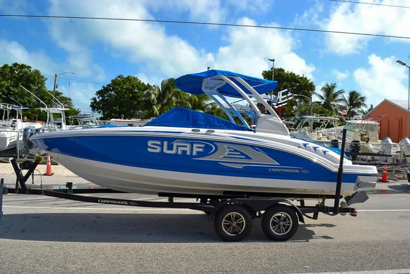 Slide: The Image of 2021 Chaparral 23 Surf boat on trailer, blue and white design, parked outdoors. - 4