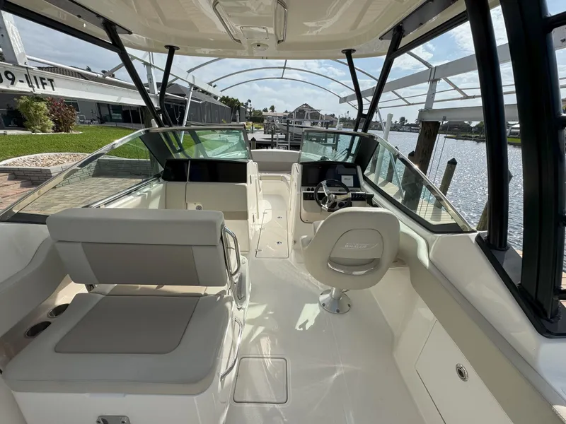 Slide: The Image of 2021 Boston Whaler 240 Vantage boat interior with seating and helm, docked by the water. - 15