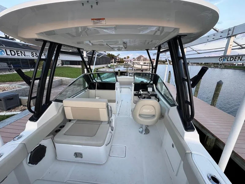 Slide: The Image of 2021 Boston Whaler 240 Vantage boat interior with seating and helm, docked by the water. - 16
