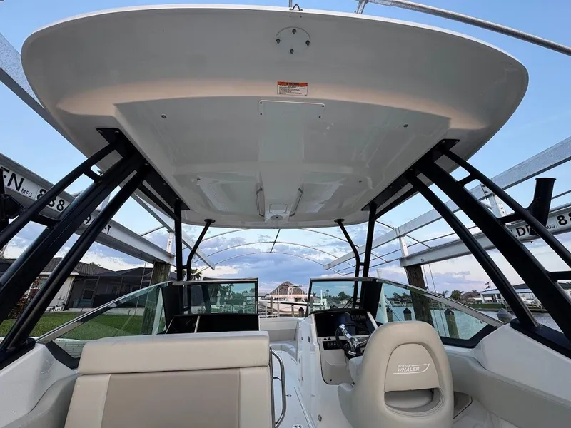 Slide: The Image of 2021 Boston Whaler 240 Vantage boat interior with seating and helm, under a canopy. - 19