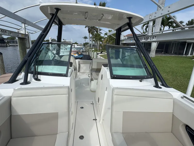 Slide: The Image of 2021 Boston Whaler 240 Vantage boat interior with seating and windshield, docked by the water. - 21
