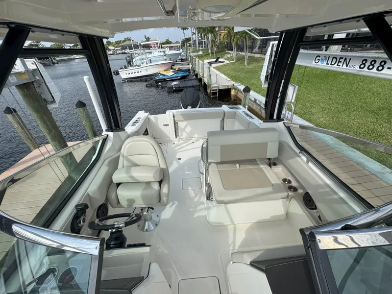 Slide: The Image of 2021 Boston Whaler 240 Vantage boat interior with seating and steering wheel, docked by the water. - 40