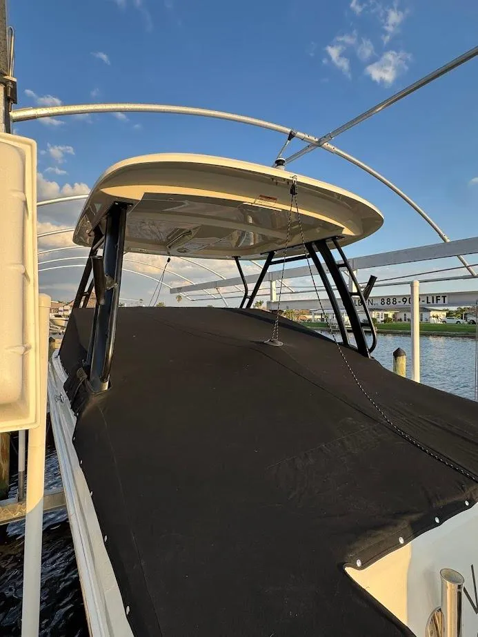 Slide: The Image of 2021 Boston Whaler 240 Vantage boat with cover, docked under a clear blue sky. - 45