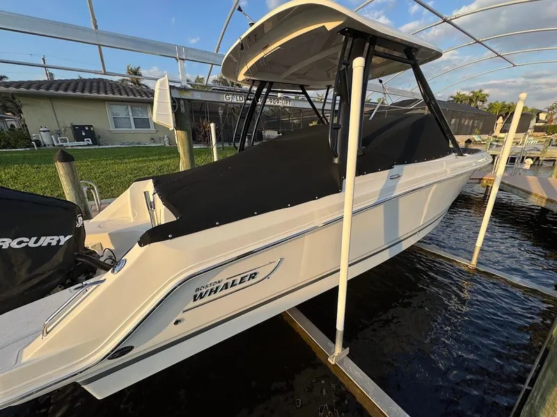 Slide: The Image of 2021 Boston Whaler 240 Vantage boat docked, covered, with Mercury engine visible. - 46