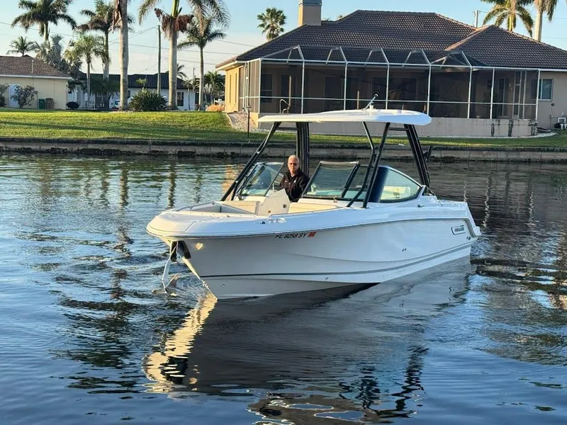 Slide: The Image of 2021 Boston Whaler 240 Vantage boat cruising on a calm waterway near a house. - 7