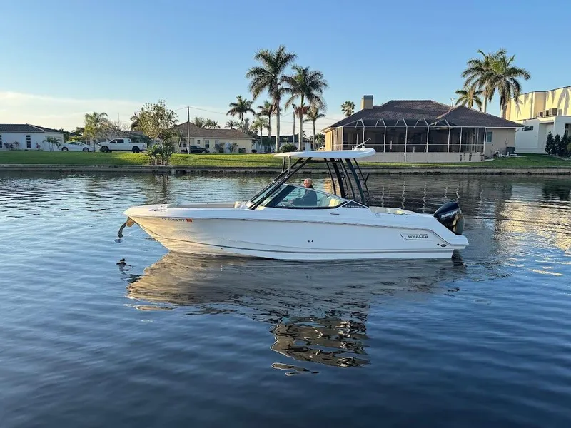 Slide: The Image of 2021 Boston Whaler 240 Vantage boat on calm water, with palm trees in the background. - 9