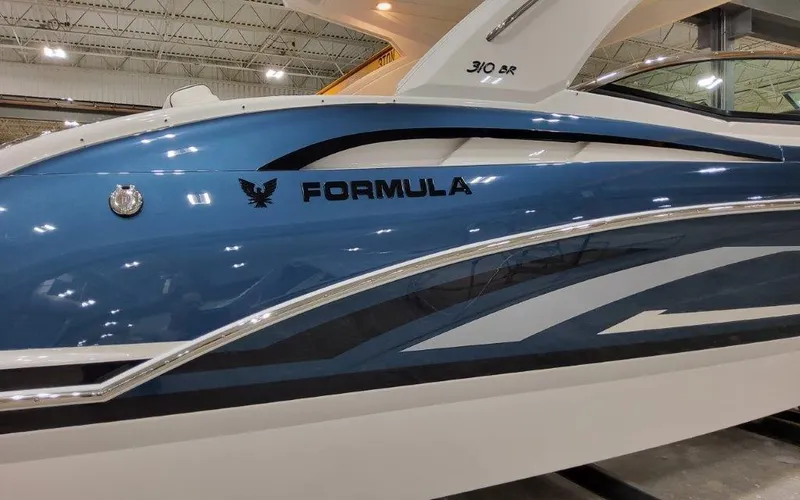 Slide: The Image of 2025 Formula 310 Bowrider I/O boat, sleek blue design, displayed indoors. - 6