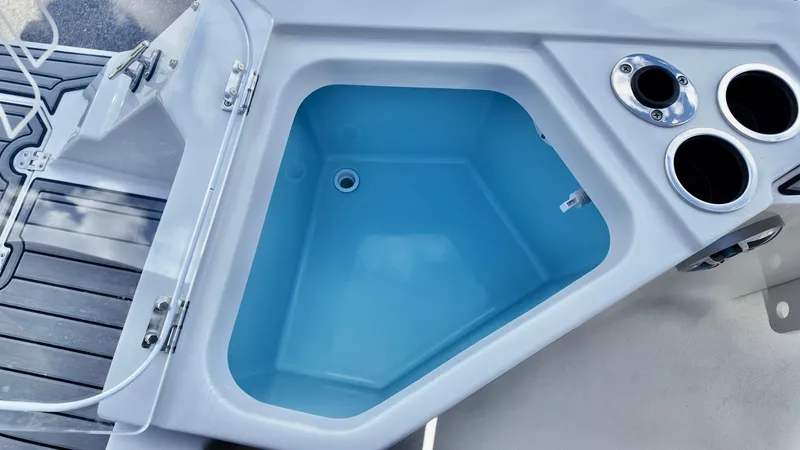 Slide: The Image of 2025 Starcraft SVX 231 OB boat interior with open storage compartment and cup holders. - 14