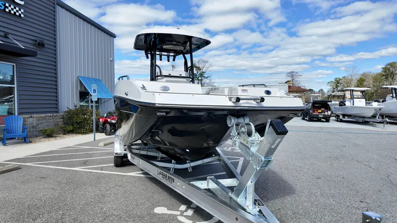 Slide: The Image of 2025 Starcraft SVX 231 OB boat on trailer, parked outside a building under a cloudy sky. - 3