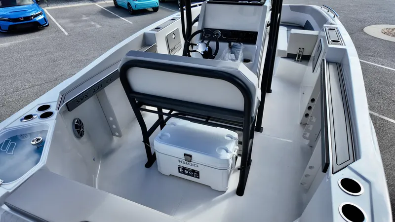 Slide: The Image of 2025 Starcraft SVX 231 OB boat interior with seating and storage in a parking lot. - 7