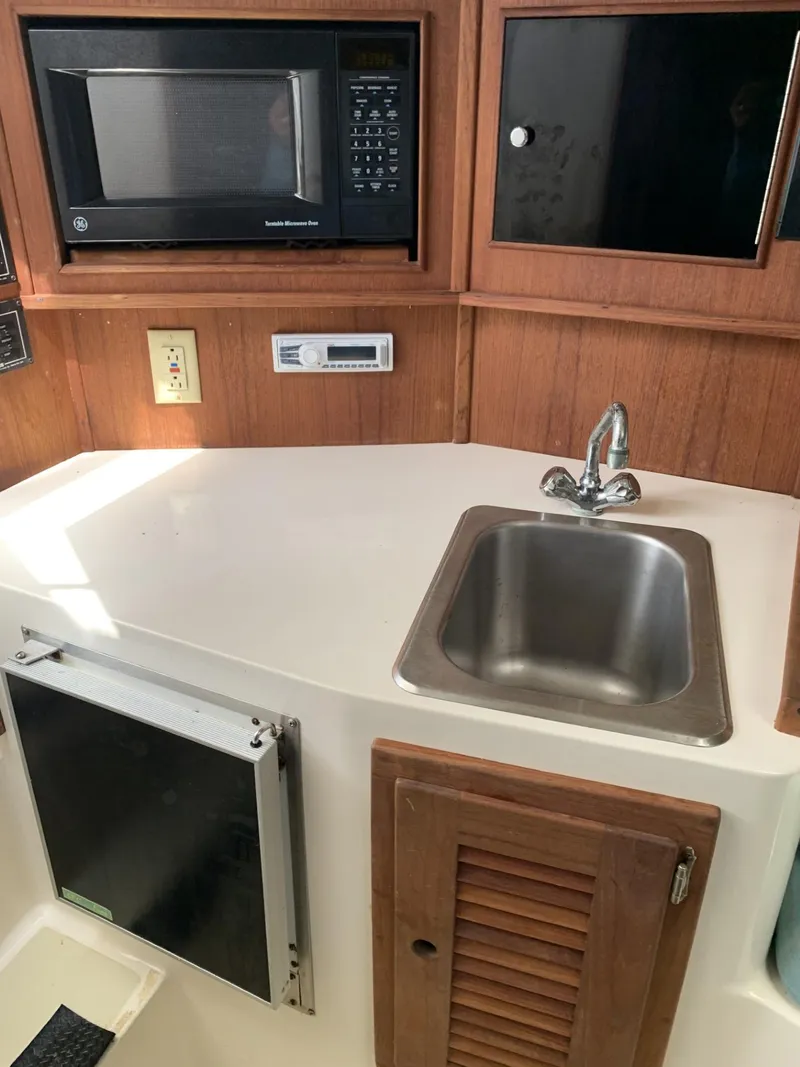 Slide: The Image of 2001 Carolina Classic 28 boat interior with sink, microwave, and storage cabinets. - 16