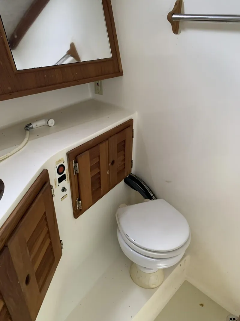 Slide: The Image of 2001 Carolina Classic 28 boat bathroom with wooden cabinets and white toilet. - 18