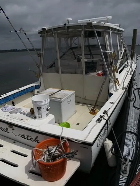 Slide: The Image of 2001 Carolina Classic 28 boat docked, equipped for fishing, with gear and storage on deck. - 2