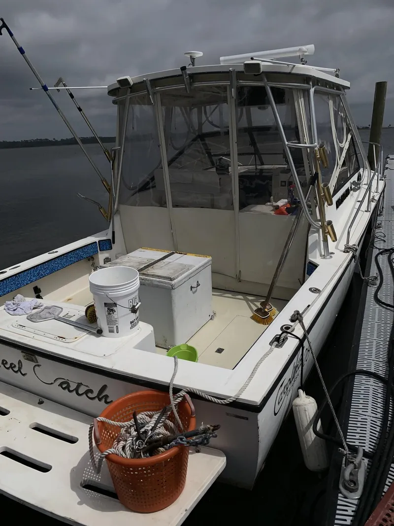 Slide: The Image of 2001 Carolina Classic 28 fishing boat docked, equipped with fishing gear and storage containers. - 3