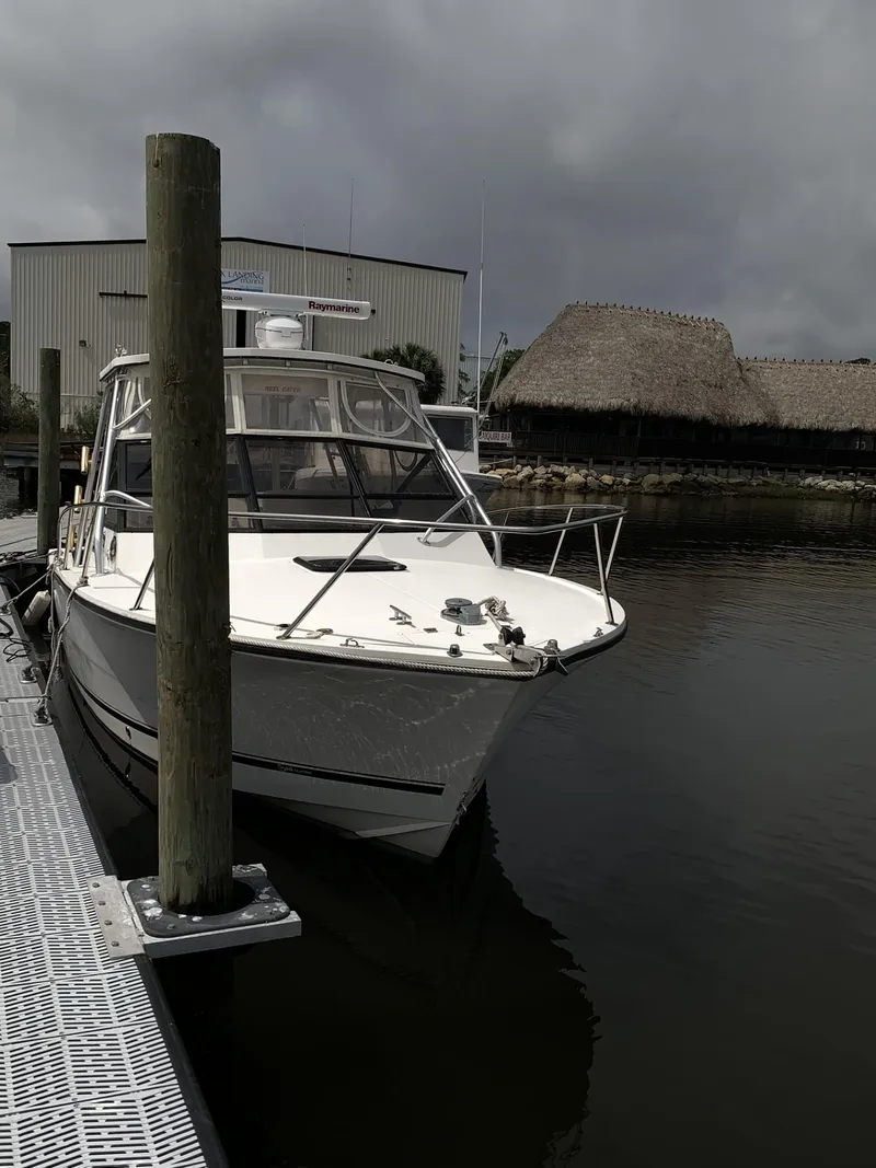 Slide: The Image of 2001 Carolina Classic 28 boat docked at marina under cloudy skies. - 37