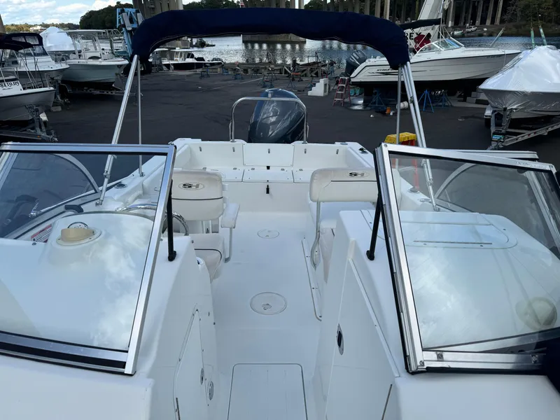 Slide: The Image of 2014 Sea Hunt Escape 235 SE boat interior at marina, featuring seating and windshield. - 11