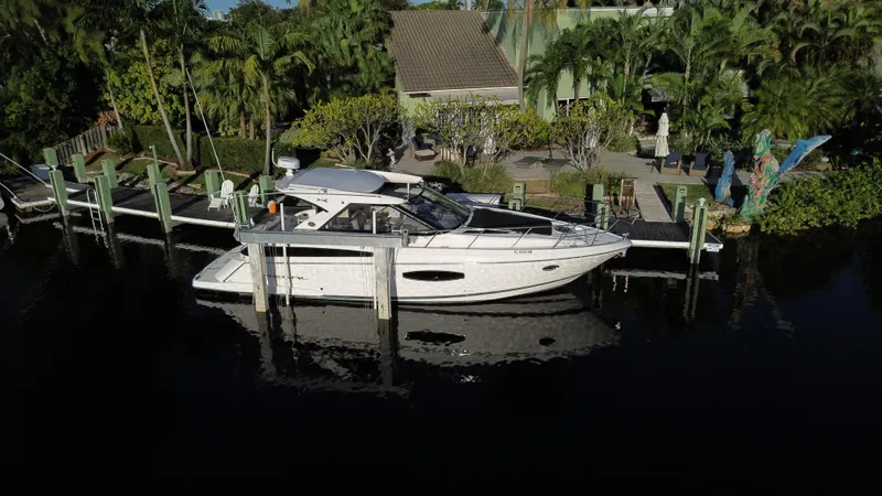 The Image of 2017 Regal 42 Sport Coupe docked near lush greenery. - 0