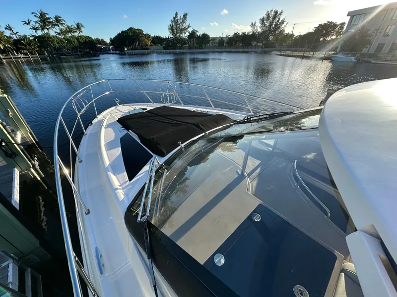 Slide: The Image of 2017 Regal 42 Sport Coupe yacht docked by a serene waterfront. - 2