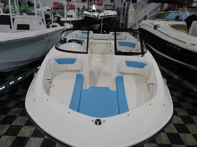 Slide: The Image of 2023 Bayliner 210EL boat with blue and white interior, displayed in a showroom. - 2