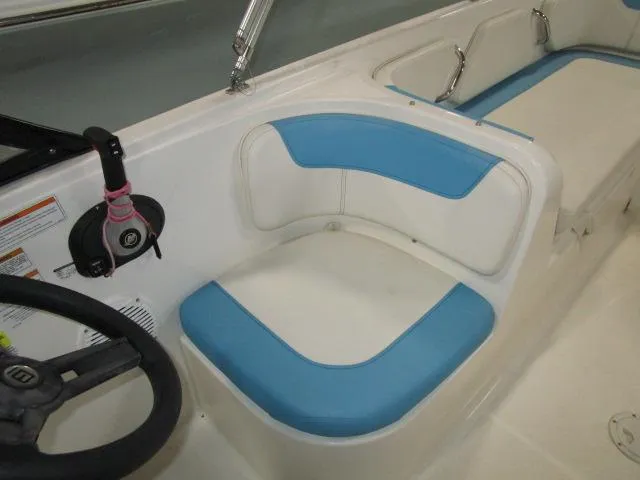 Slide: The Image of 2023 Bayliner 210EL boat interior with blue and white seating and steering wheel. - 9