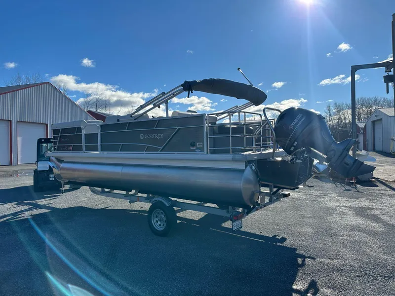 Slide: The Image of 2023 Godfrey SWEETWATER 2286 SFL pontoon boat on trailer under sunny sky. - 2