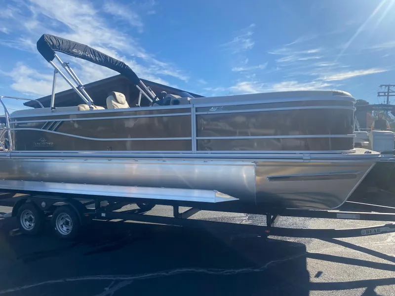Slide: The Image of 2025 SunCatcher Select 322RC pontoon boat on trailer under clear blue sky. - 3