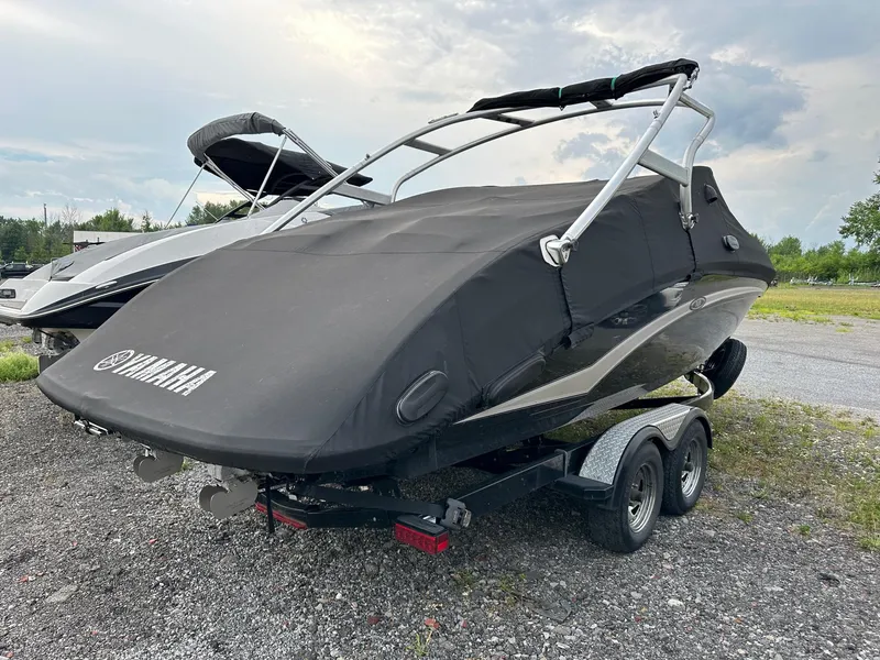 Slide: The Image of 2012 Yamaha Boats 242 Limited S covered on trailer, parked outdoors. - 4