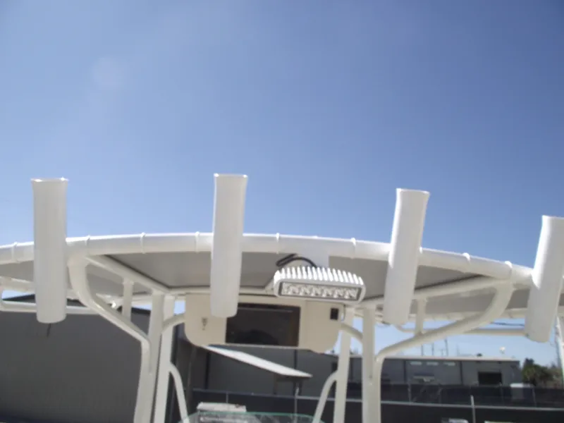 Slide: The Image of 2012 Sea Hunt Ultra 211 boat T-top with rod holders under clear blue sky. - 42