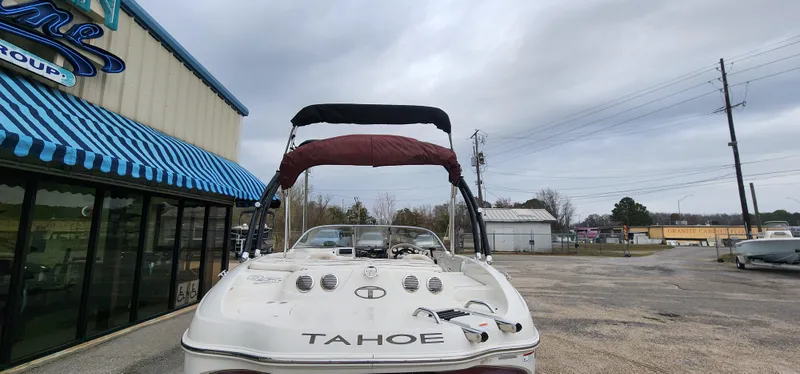 Slide: The Image of 2014 Tahoe Q5i boat parked outside a building with blue-striped awning. - 11