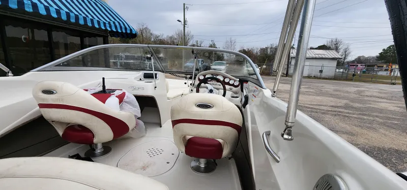 Slide: The Image of Interior of 2014 Tahoe Q5i boat with red and white seating, parked outdoors. - 12