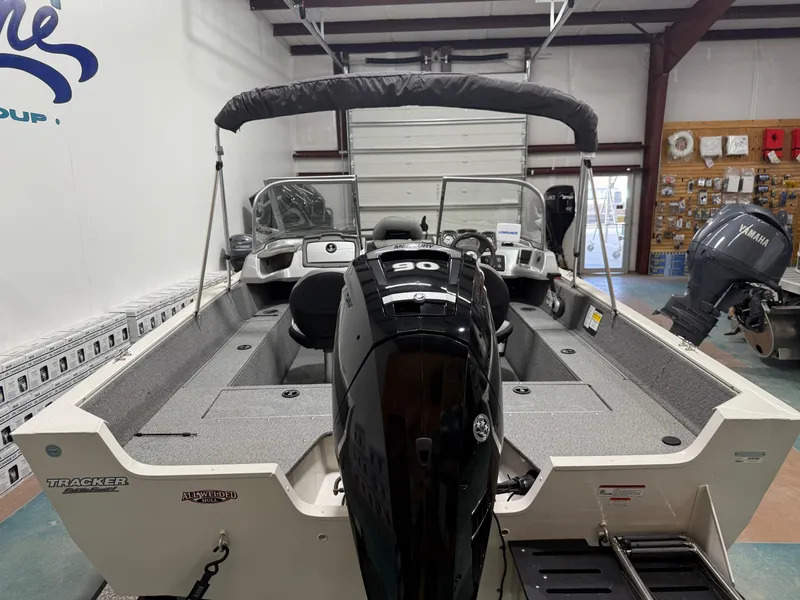 Slide: The Image of 2018 Tracker Pro Guide V 165 WT boat in showroom, featuring a powerful outboard motor. - 5