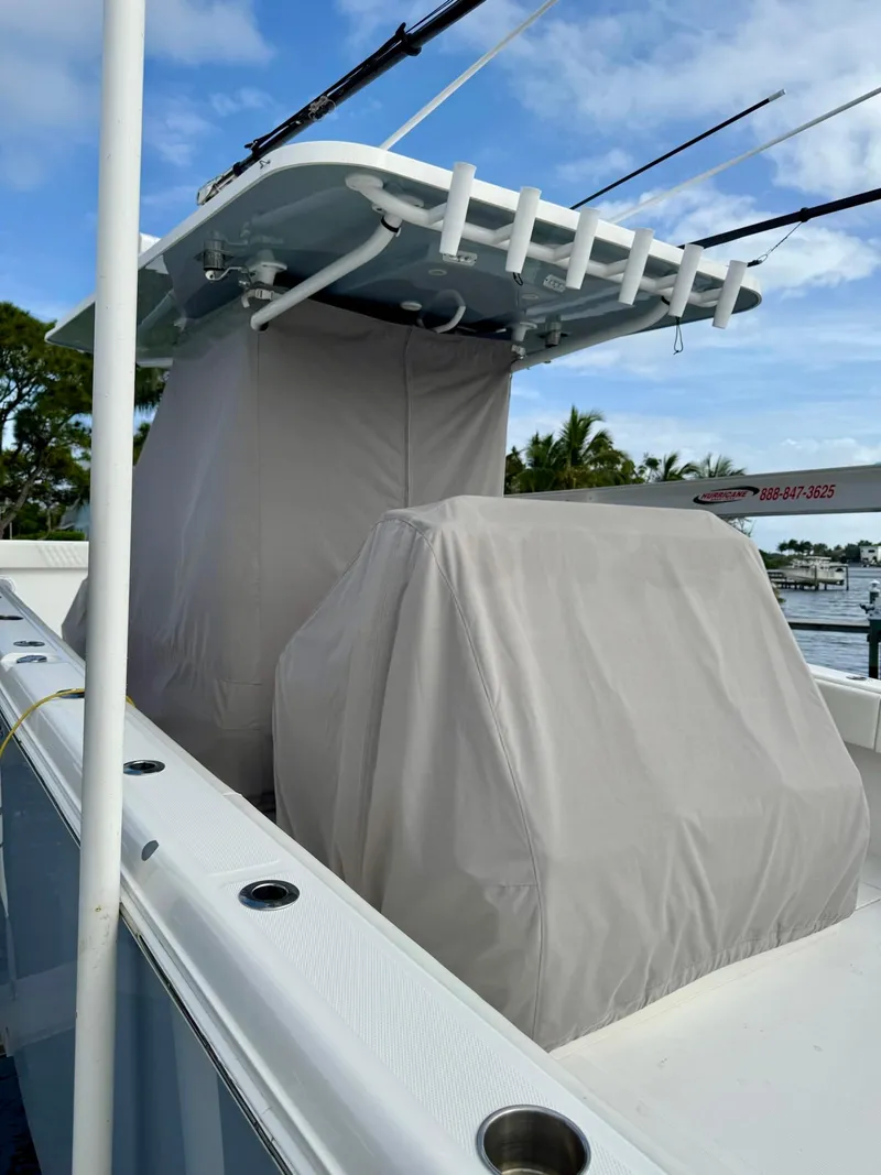 Slide: The Image of 2022 Invincible 33 Catamaran with covered console and seating, docked by the water. - 31