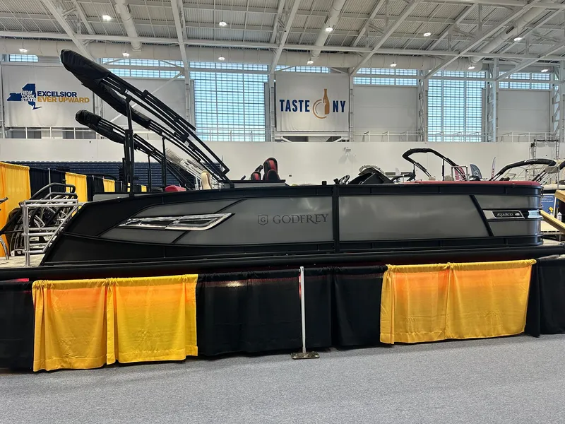 The Image of 2024 Godfrey AquaPatio 235 SFLC pontoon boat displayed indoors at a boat show. - 0