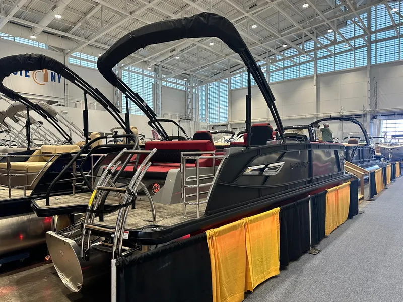 Slide: The Image of 2024 Godfrey AquaPatio 235 SFLC pontoon boat displayed indoors at a boat show. - 2