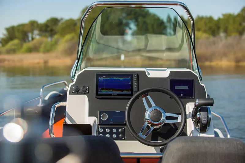 Slide: The Image of 2025 Zodiac Medline 6.8 boat dashboard with steering wheel and navigation screens. - 2