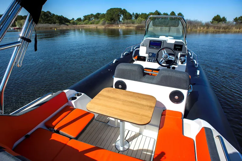 Slide: The Image of 2025 Zodiac Medline 6.8 boat interior with seating and table on calm water. - 5