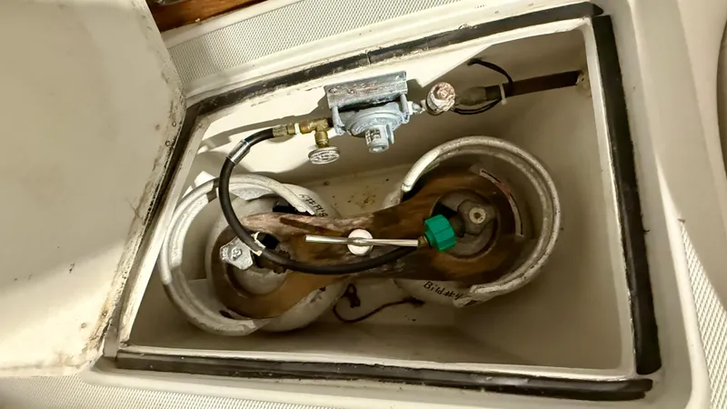 Slide: The Image of 1989 J Boats J/40 propane tank compartment with connected hoses and regulator. - 12