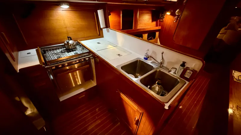Slide: The Image of 1989 J Boats J/40 yacht kitchen with stove, dual sinks, and wooden cabinetry. - 19