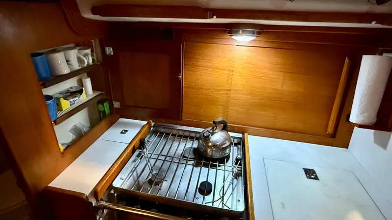Slide: The Image of 1989 J Boats J/40 yacht kitchen with stove, kettle, and wooden cabinetry. - 23